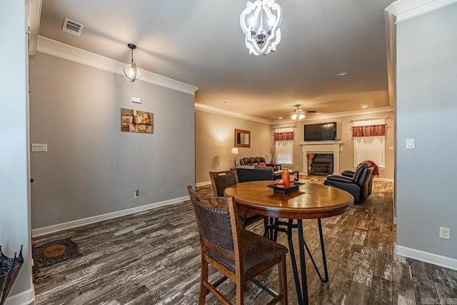 dining space with dark hardwood / wood-style flooring, crown molding, and ceiling fan with notable chandelier