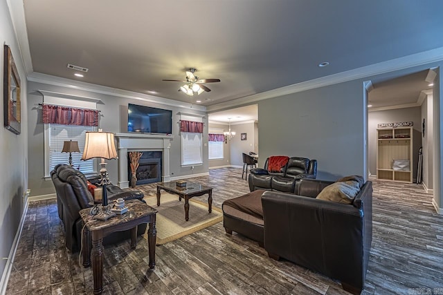 living room with a fireplace, dark hardwood / wood-style floors, ceiling fan with notable chandelier, and ornamental molding