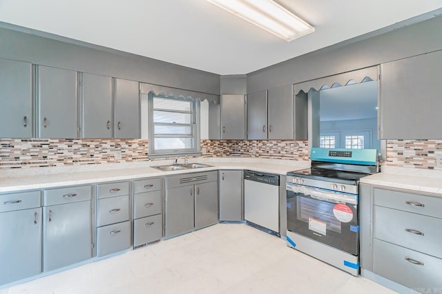 kitchen featuring appliances with stainless steel finishes, gray cabinetry, plenty of natural light, backsplash, and sink