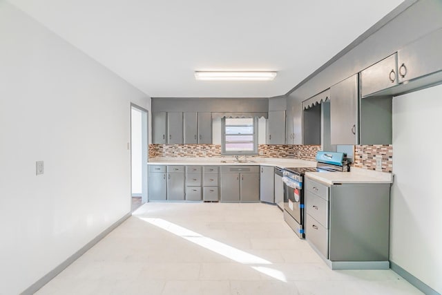 kitchen with stainless steel appliances, gray cabinetry, backsplash, and sink