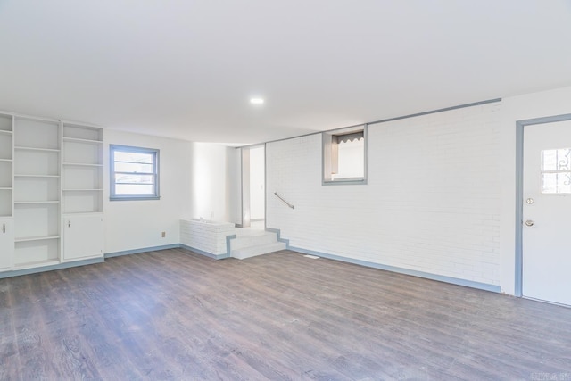 basement featuring brick wall and hardwood / wood-style floors