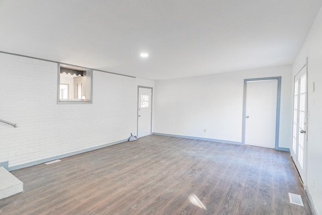 unfurnished room with brick wall and dark hardwood / wood-style floors