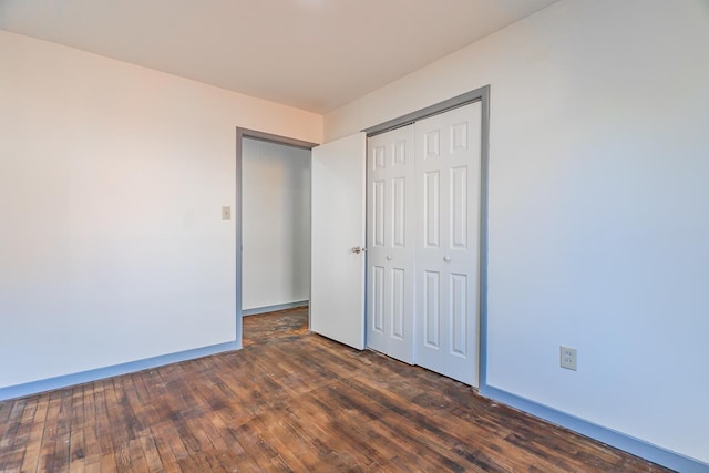 unfurnished bedroom featuring a closet and dark wood-type flooring