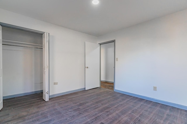 unfurnished bedroom with dark wood-type flooring and a closet