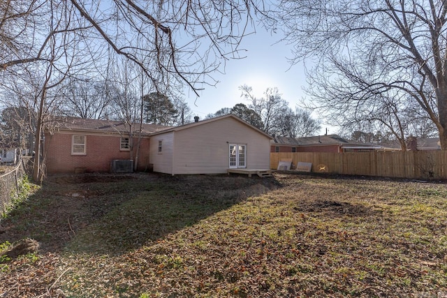 rear view of property featuring cooling unit and a yard