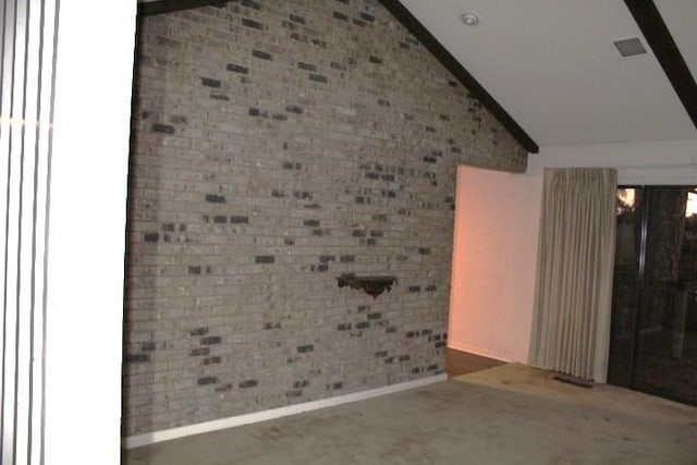 empty room featuring lofted ceiling and brick wall