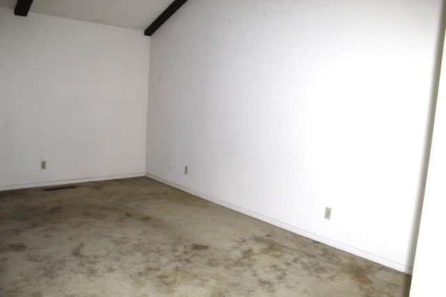 carpeted empty room featuring vaulted ceiling with beams