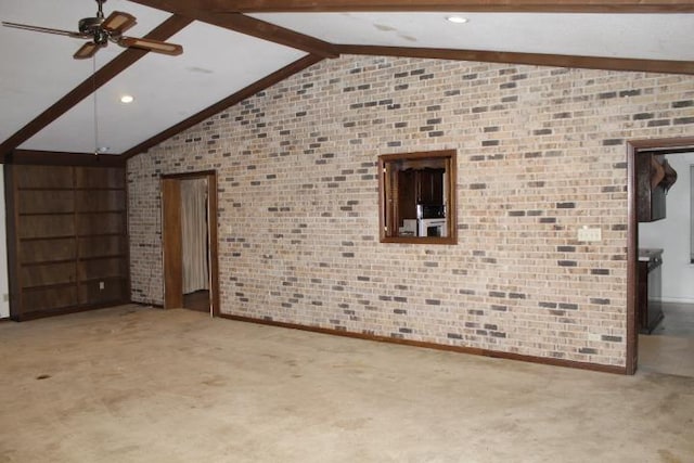 interior space with ceiling fan, brick wall, carpet flooring, and vaulted ceiling with beams