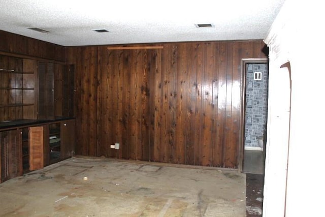 spare room featuring a textured ceiling and wood walls