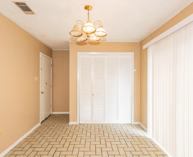 unfurnished bedroom featuring a closet, a chandelier, and ornamental molding