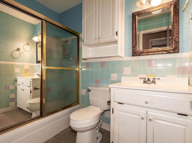 full bathroom featuring toilet, vanity, tile walls, and shower / bath combination with glass door