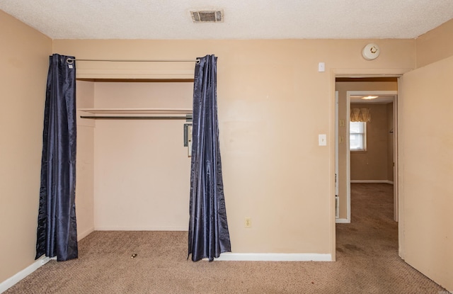 unfurnished bedroom with a textured ceiling, a closet, and light carpet