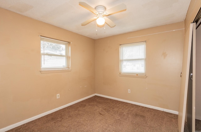 spare room with ceiling fan, plenty of natural light, and carpet flooring