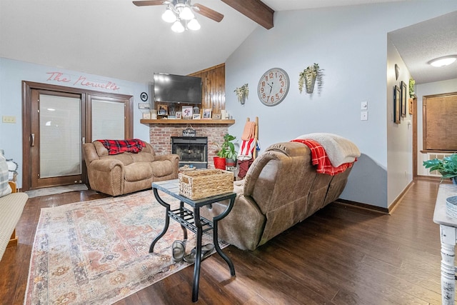 living room featuring dark wood-type flooring, a brick fireplace, ceiling fan, and lofted ceiling with beams