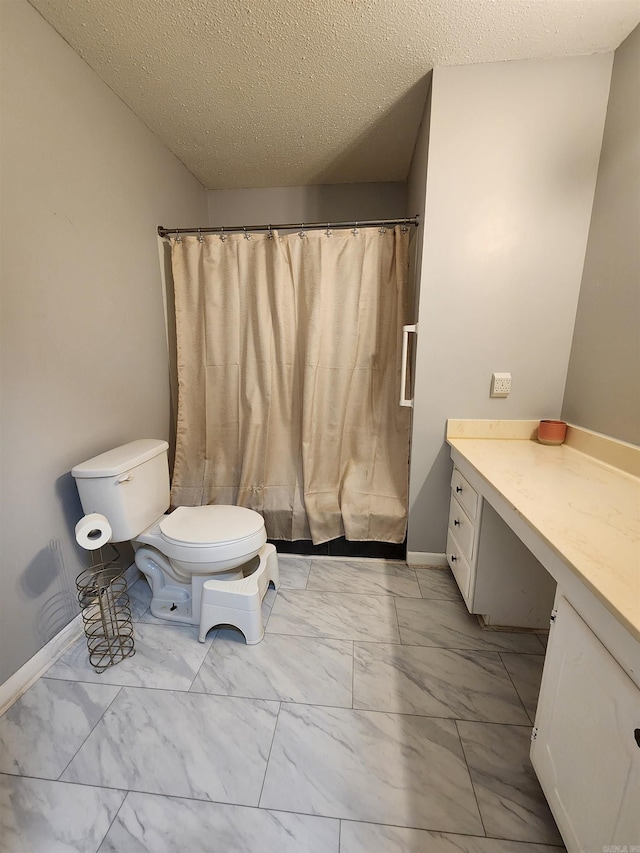 bathroom with vanity, toilet, and a textured ceiling