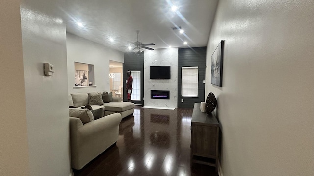 living room with ceiling fan, dark hardwood / wood-style flooring, a premium fireplace, and a high ceiling