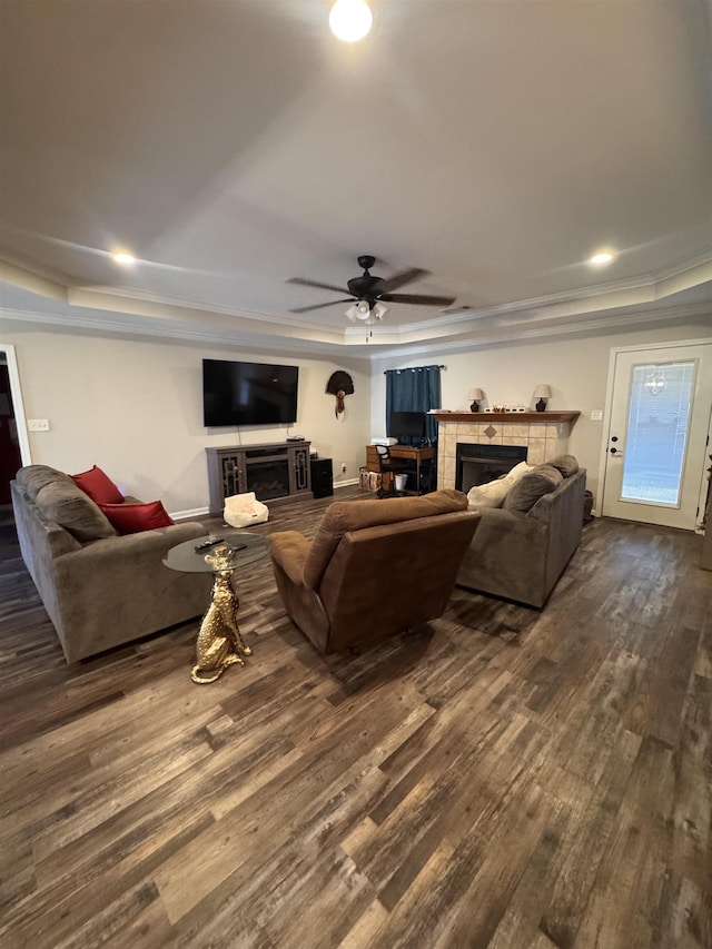 living room with ceiling fan, a tray ceiling, dark hardwood / wood-style floors, and a fireplace