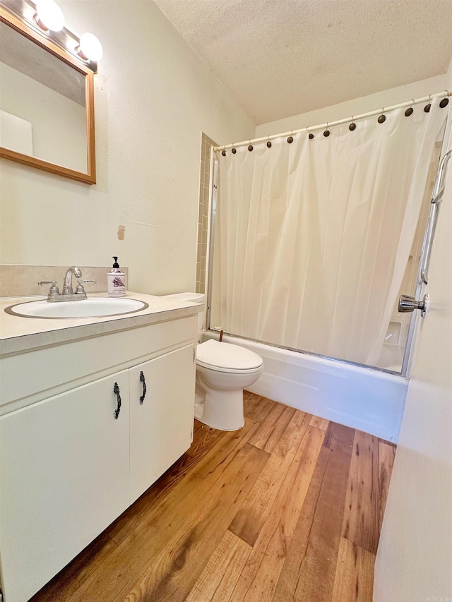 full bathroom with toilet, hardwood / wood-style floors, shower / bathtub combination with curtain, a textured ceiling, and vanity