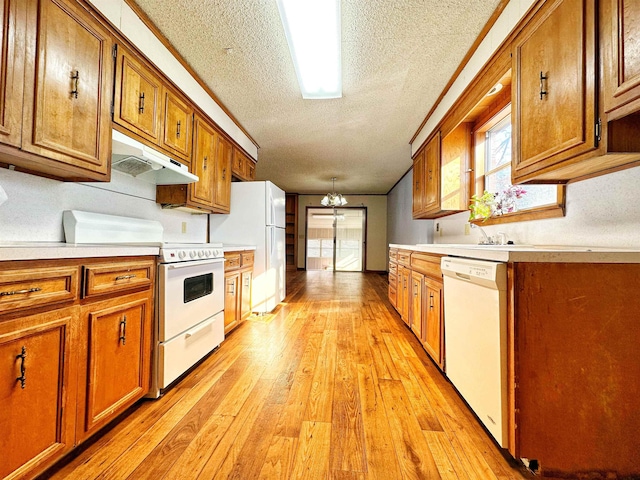 kitchen featuring a notable chandelier, white appliances, a textured ceiling, ornamental molding, and light hardwood / wood-style flooring