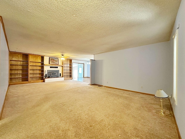 unfurnished living room featuring a textured ceiling, built in features, carpet, and a fireplace