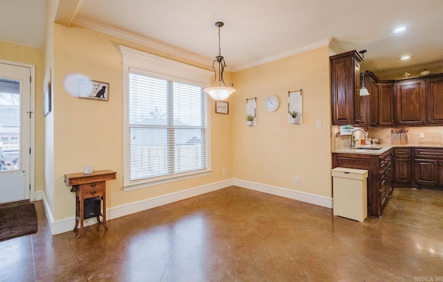 kitchen featuring decorative light fixtures, dark brown cabinets, ornamental molding, and sink