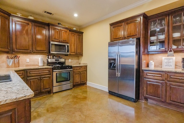 kitchen with stainless steel appliances, ornamental molding, light stone counters, and tasteful backsplash