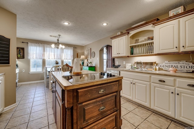 kitchen featuring black electric cooktop, a chandelier, a kitchen island, pendant lighting, and sink