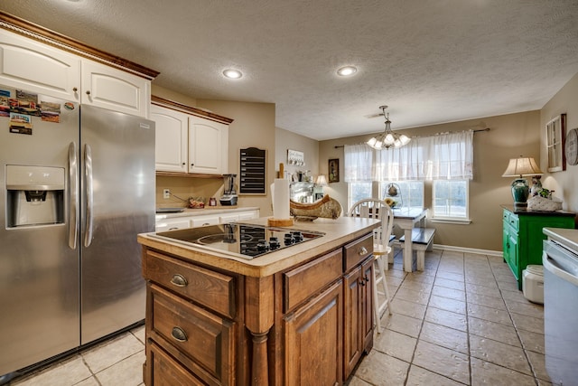 kitchen featuring a textured ceiling, dishwasher, stainless steel refrigerator with ice dispenser, a notable chandelier, and black electric cooktop