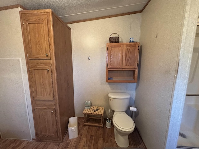 bathroom with toilet, a textured ceiling, ornamental molding, and hardwood / wood-style flooring