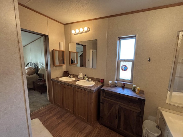 bathroom with vanity, a textured ceiling, ornamental molding, and hardwood / wood-style flooring