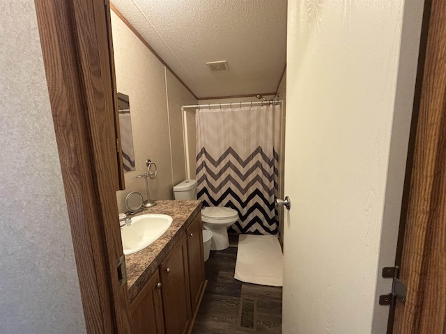 bathroom featuring toilet, vanity, hardwood / wood-style floors, a shower with curtain, and a textured ceiling