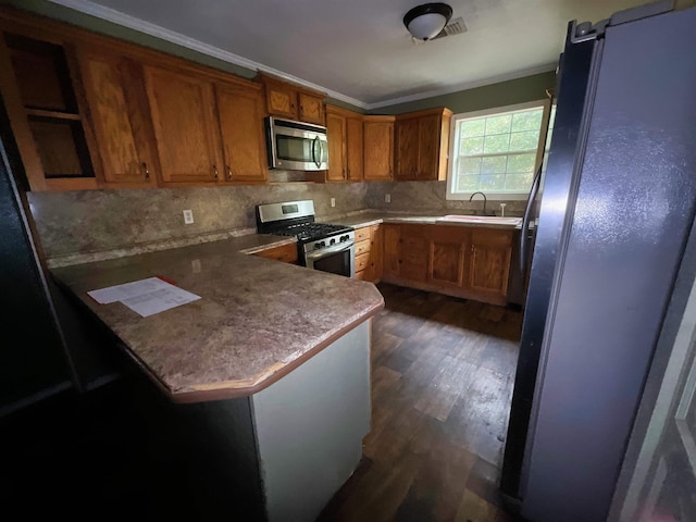 kitchen featuring kitchen peninsula, appliances with stainless steel finishes, dark hardwood / wood-style flooring, and ornamental molding