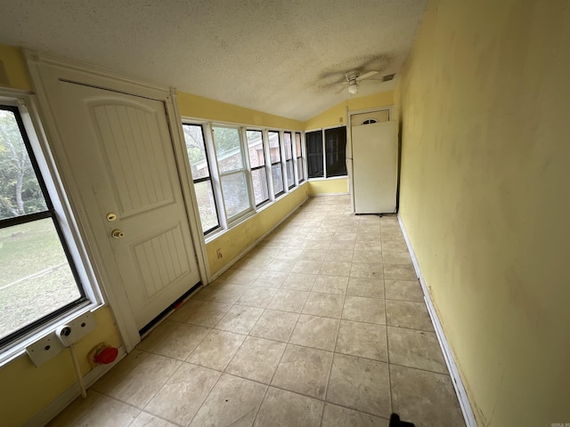 corridor featuring light tile patterned flooring, a textured ceiling, and vaulted ceiling