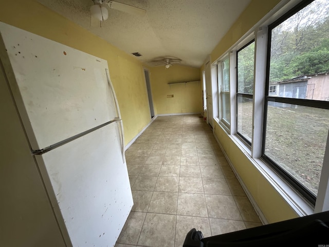 unfurnished sunroom featuring lofted ceiling, a healthy amount of sunlight, and ceiling fan