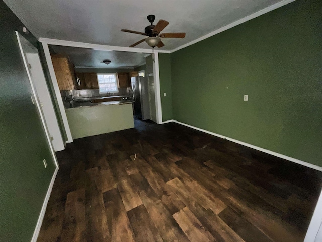 unfurnished living room featuring ceiling fan, dark wood-type flooring, and crown molding