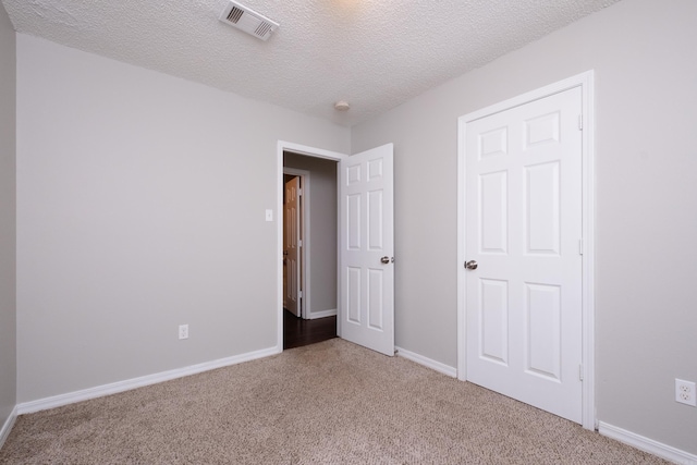 unfurnished bedroom featuring a textured ceiling and light carpet