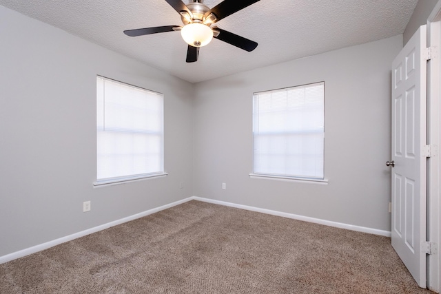 spare room with a textured ceiling, ceiling fan, carpet, and a healthy amount of sunlight