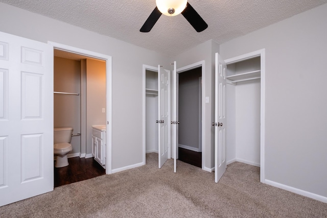 unfurnished bedroom with ceiling fan, carpet floors, ensuite bathroom, two closets, and a textured ceiling