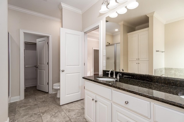 bathroom featuring toilet, vanity, a shower with door, and crown molding