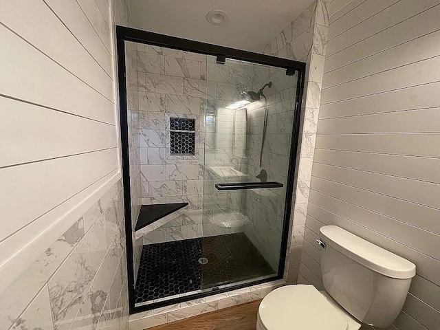 bathroom featuring toilet, wood walls, and an enclosed shower