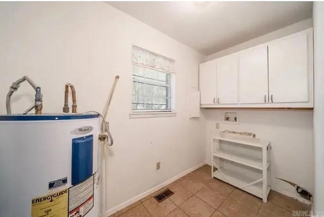 laundry area featuring light tile patterned floors, cabinets, and electric water heater