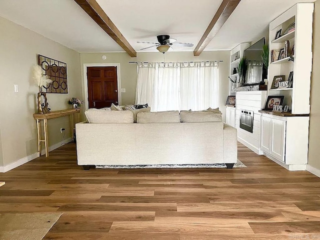 living room with ceiling fan, beamed ceiling, and hardwood / wood-style floors