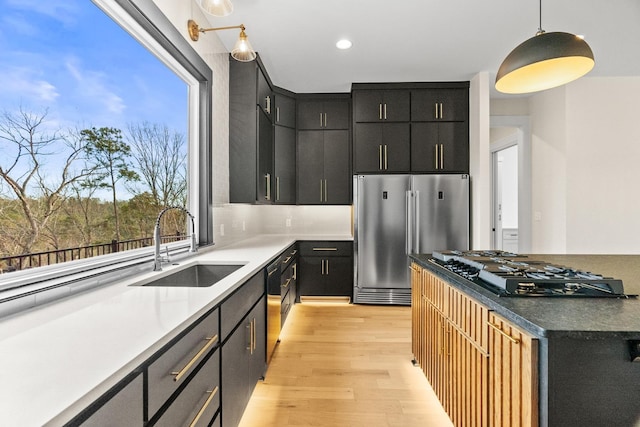 kitchen featuring light hardwood / wood-style flooring, appliances with stainless steel finishes, sink, and pendant lighting