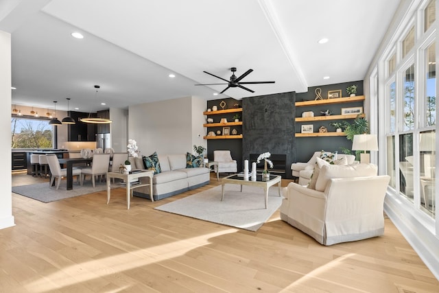 living room with light wood-type flooring, ceiling fan, beverage cooler, and plenty of natural light