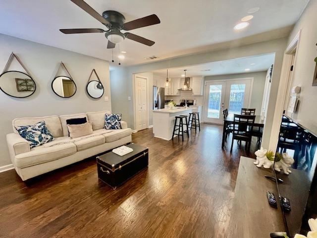 living room featuring ceiling fan, dark hardwood / wood-style floors, and french doors