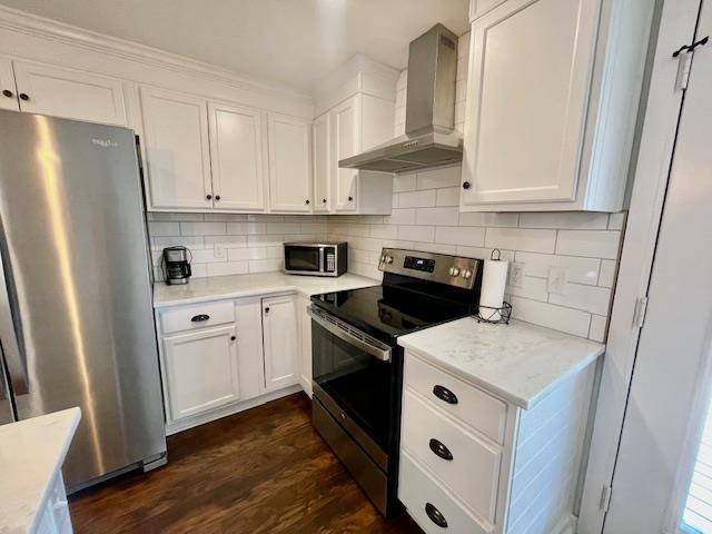 kitchen with dark hardwood / wood-style floors, stainless steel appliances, white cabinetry, and wall chimney range hood