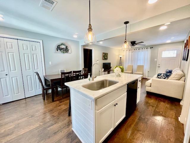 kitchen with a center island with sink, black dishwasher, hanging light fixtures, white cabinets, and sink