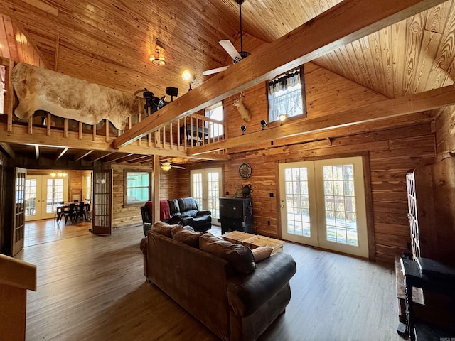 living room with wood ceiling, wood walls, hardwood / wood-style floors, ceiling fan, and french doors