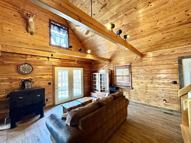 living room with wooden ceiling, a wood stove, wooden walls, and lofted ceiling with beams