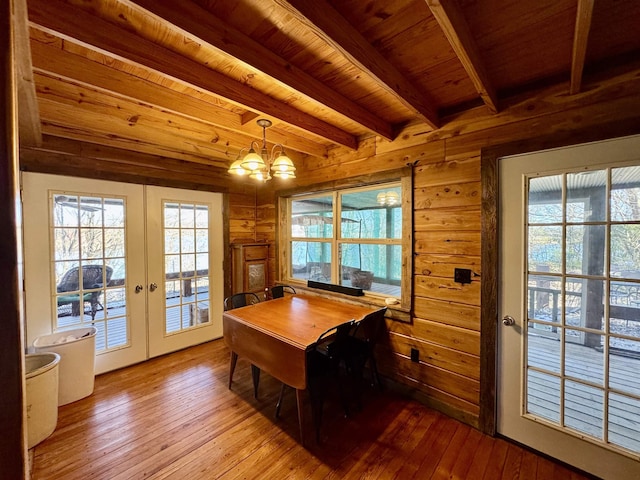 dining area with beam ceiling, light hardwood / wood-style flooring, french doors, a chandelier, and wooden ceiling